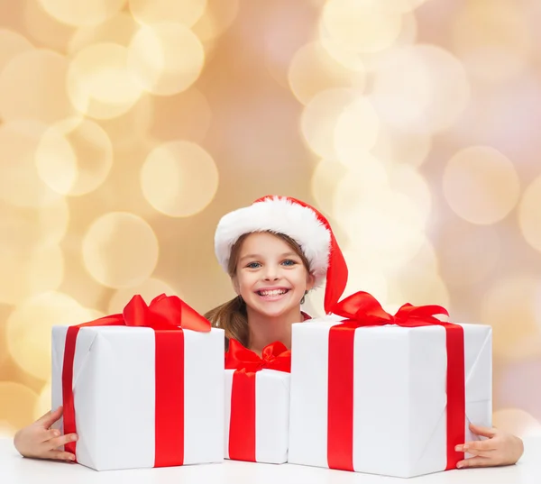 Sonriente chica en santa helper sombrero con cajas de regalo — Foto de Stock