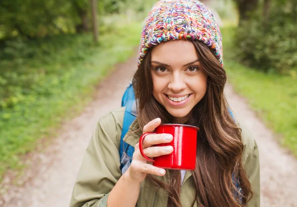 Gülümseyen genç kadın kupa ve hiking sırt çantası — Stok fotoğraf