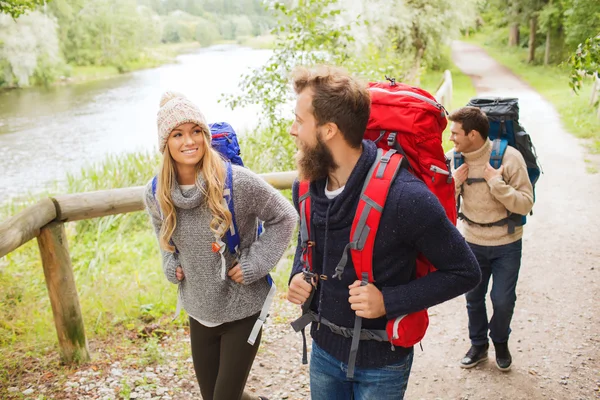 Groep lachende vrienden met rugzakken wandelen — Stockfoto