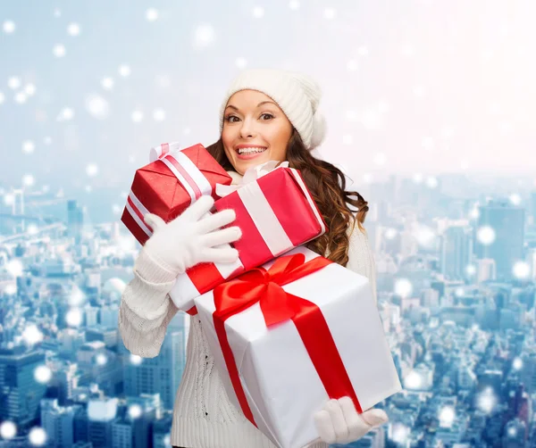 Souriant jeune femme dans santa chapeau d'aide avec des cadeaux — Photo