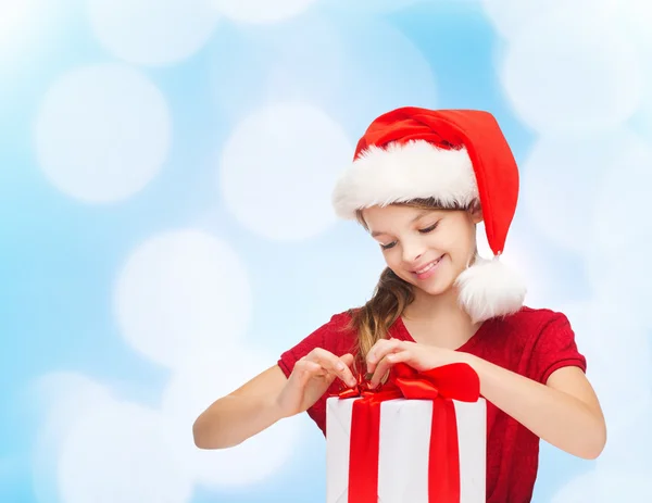 Chica sonriente en sombrero de ayudante de santa con caja de regalo —  Fotos de Stock