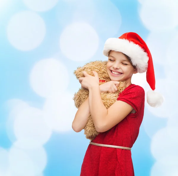 Smiling girl in santa helper hat with teddy bear — Stock Photo, Image