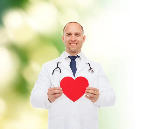 Médico varón sonriente con corazón rojo y estetoscopio — Foto de Stock