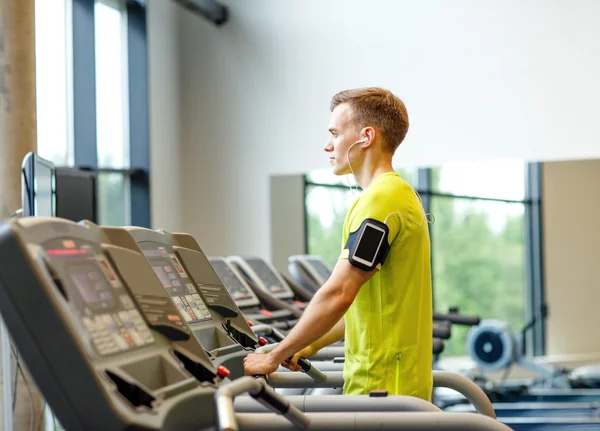 Hombre con smartphone haciendo ejercicio en la cinta de correr en el gimnasio — Foto de Stock