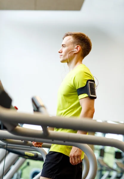 Muž s smartphone cvičení na běžeckém pásu v tělocvičně — Stock fotografie