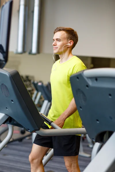 Hombre con smartphone haciendo ejercicio en la cinta de correr en el gimnasio — Foto de Stock