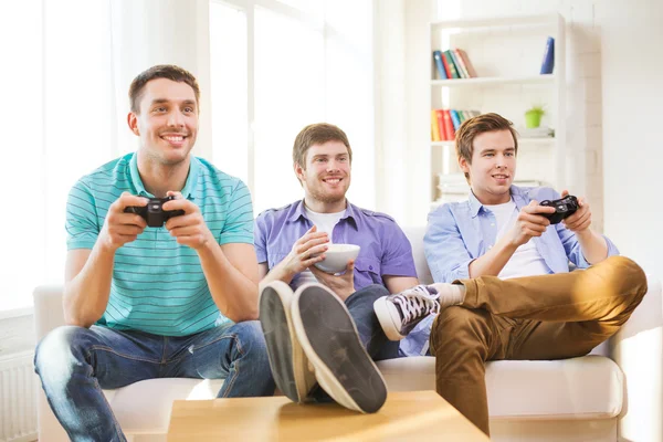 Amici sorridenti che giocano ai videogiochi a casa — Foto Stock
