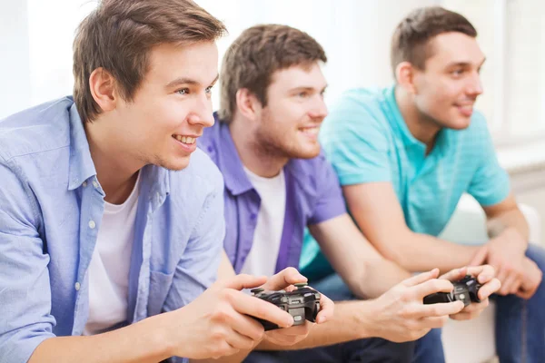 Lächelnde Freunde, die zu Hause Videospiele spielen — Stockfoto