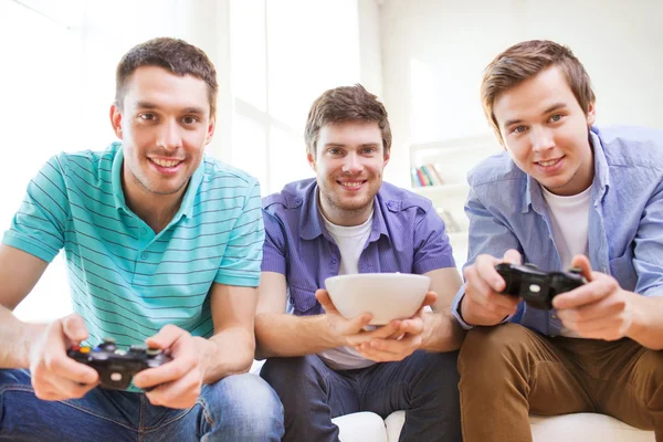 Amici sorridenti che giocano ai videogiochi a casa — Foto Stock