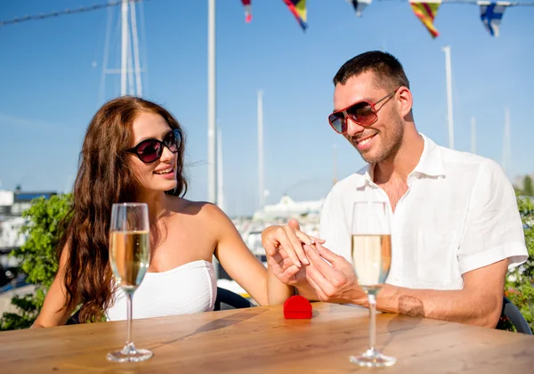 Usmívající se pár s šampaňským a dar v kavárně — Stock fotografie