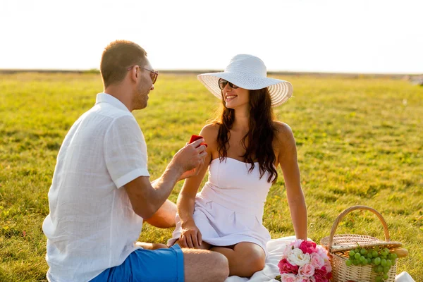 Coppia sorridente con piccola scatola regalo rossa su picnic — Foto Stock