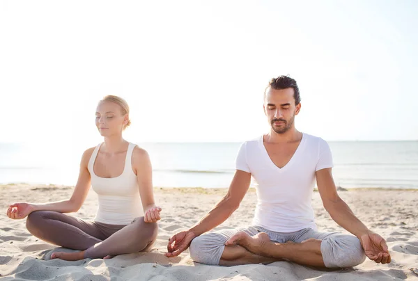 Pareja sonriente haciendo ejercicios de yoga al aire libre —  Fotos de Stock