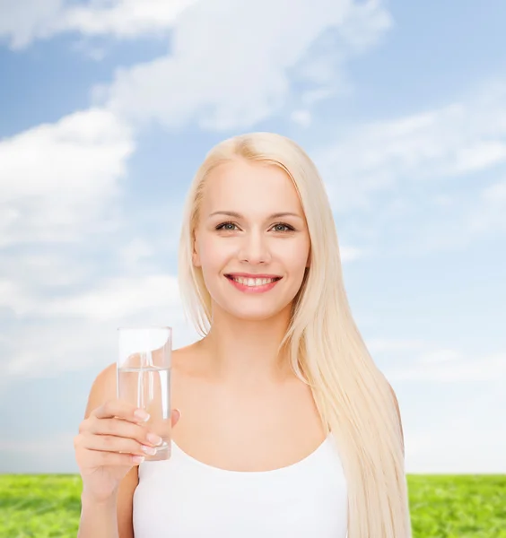Młoda kobieta uśmiechający się z szklanką wody — Zdjęcie stockowe