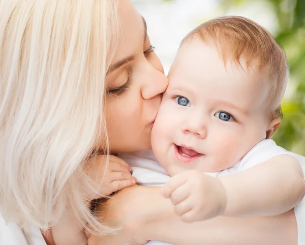 Glückliche Mutter küsst lächelndes Baby — Stockfoto