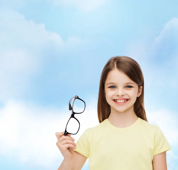 Smiling cute little girl holding black eyeglasses — Stock Photo, Image