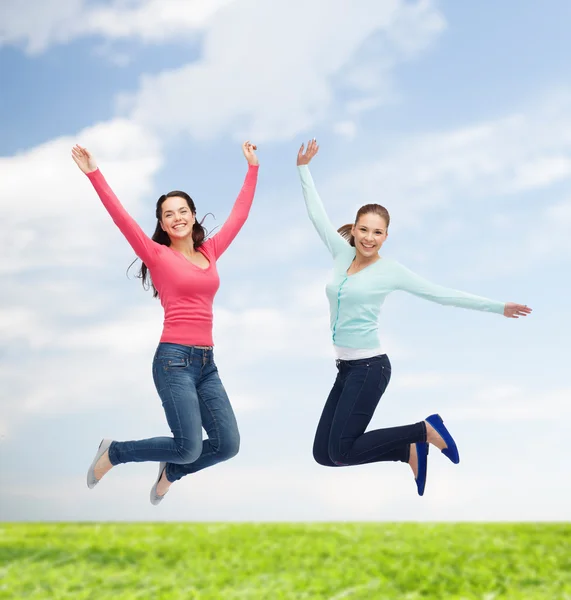 Sonrientes mujeres jóvenes saltando en el aire — Foto de Stock