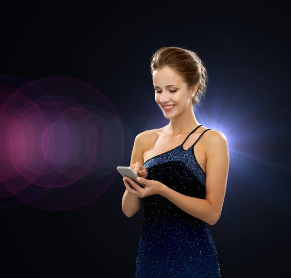 Улыбающаяся женщина в вечернем платье со смартфоном — стоковое фото