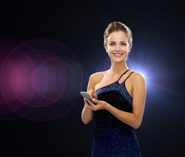 Mujer sonriente en vestido de noche con teléfono inteligente — Foto de Stock