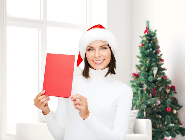 Lachende vrouw in kerstmuts met een wenskaart — Stockfoto