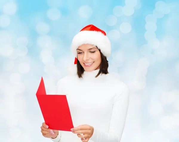 Usmívající se žena v santa hat s přání — Stock fotografie