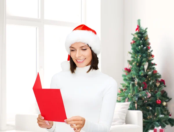 Donna sorridente in cappello di Babbo Natale con biglietto di auguri — Foto Stock