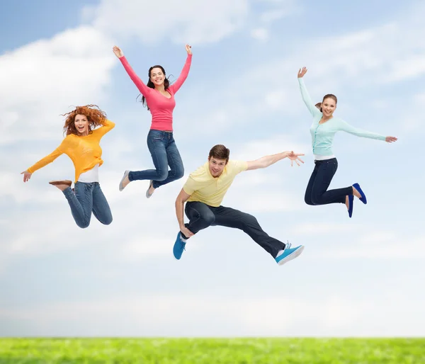 Gruppe lächelnder Teenager springt in die Luft lizenzfreie Stockbilder