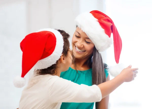 在圣诞老人的助手帽子中拥抱母亲和女儿 — 图库照片