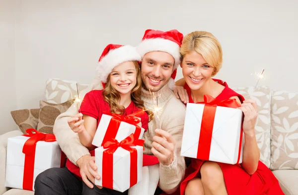 Familia sonriente sosteniendo cajas de regalo y destellos —  Fotos de Stock