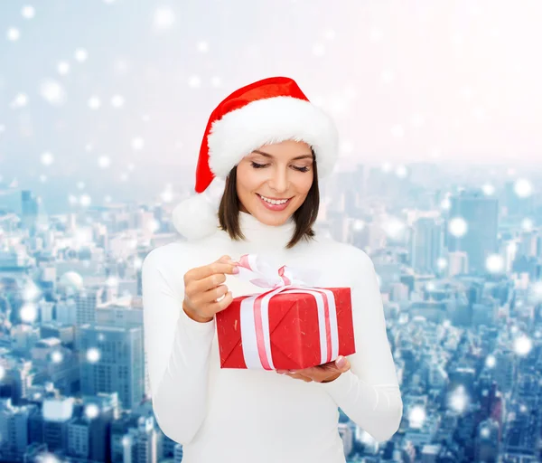 Femme souriante en santa chapeau d'aide avec boîte cadeau — Photo