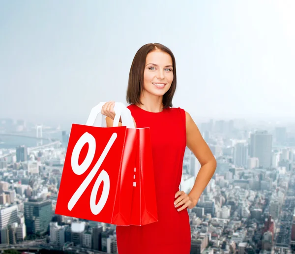 Mujer en vestido rojo con bolsas de compras — Foto de Stock