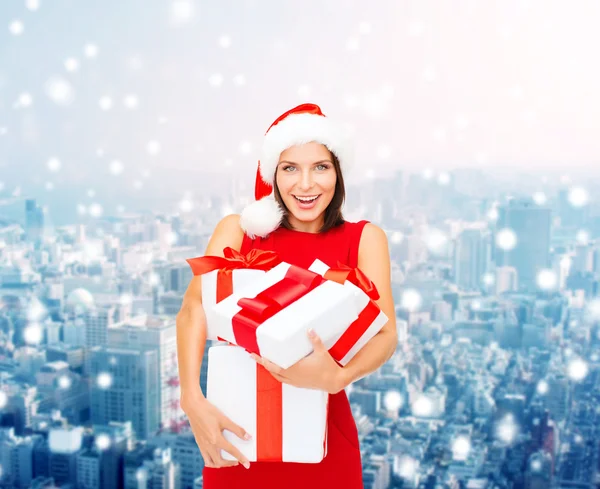 Mujer sonriente en sombrero de ayudante de santa con cajas de regalo — Foto de Stock