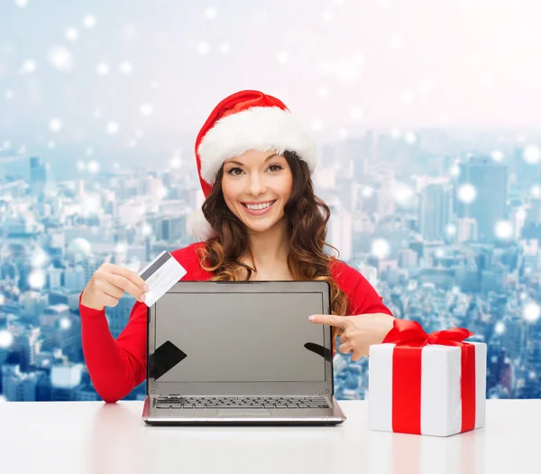 Mujer sonriente en sombrero de santa con regalo y portátil — Foto de Stock