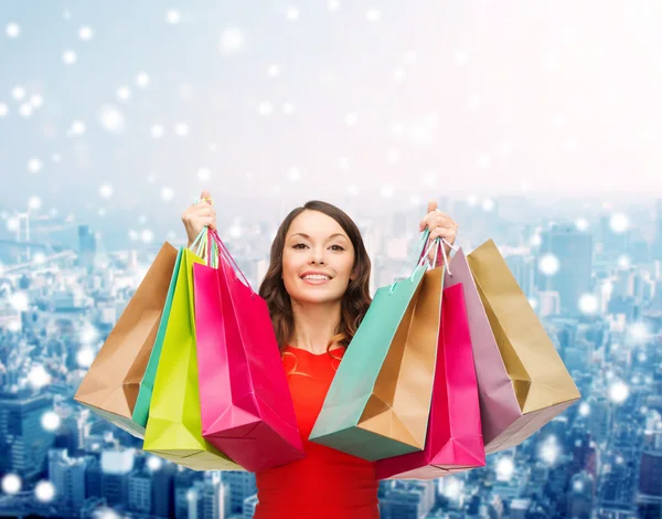 Mulher sorridente com sacos de compras coloridos — Fotografia de Stock