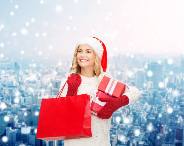 微笑在圣诞老人的助手帽子与礼品的年轻女子 — 图库照片