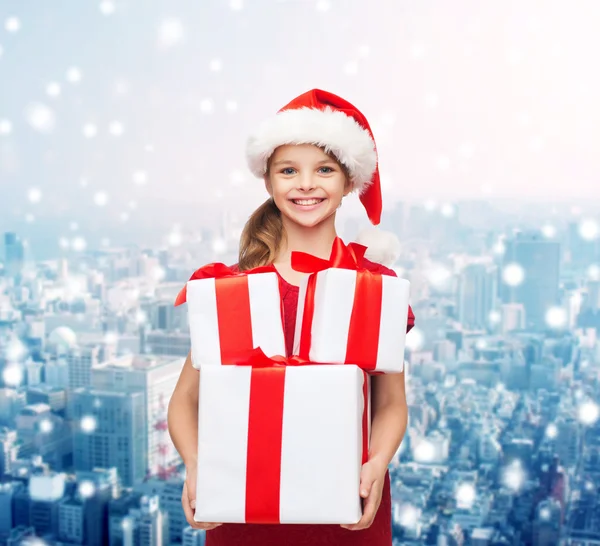 Smiling little girl in santa helper hat with gifts — Stock Photo, Image