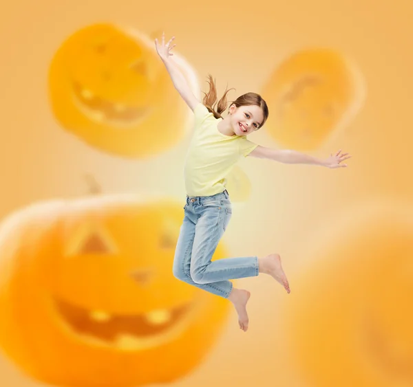 Smiling girl jumping over pumpkins background — Stock Photo, Image