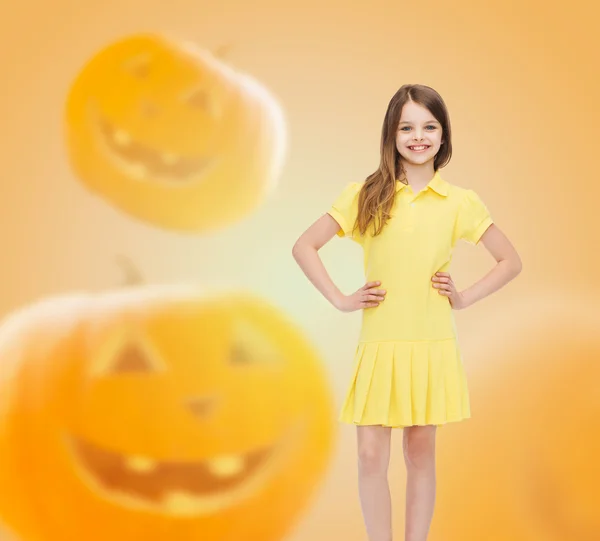 Smiling girl in dress over pumpkins background — Stock Photo, Image