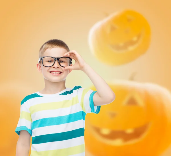 Sorrindo menino em óculos sobre abóboras fundo — Fotografia de Stock