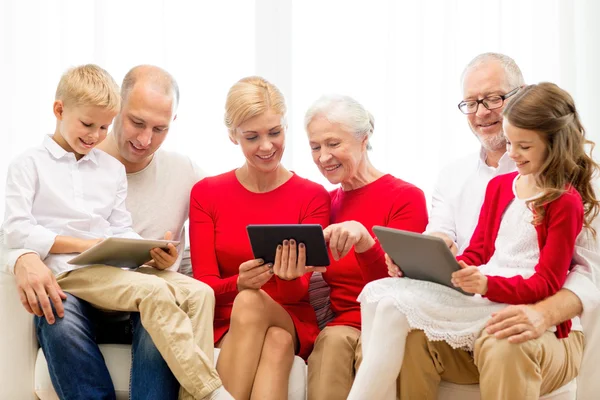 Улыбающаяся семья с планшетными компьютерами дома — стоковое фото