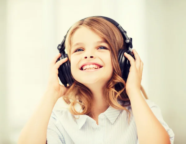 Sorrindo menina com fones de ouvido em casa — Fotografia de Stock