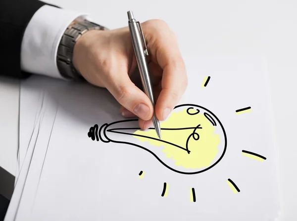 Close up of male hand with pen drawing bulb — Stock Photo, Image