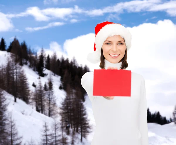 Žena v pomocníka čepice santa s prázdnou červenou kartu — Stock fotografie