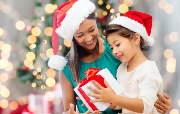 Felice madre e ragazza in cappelli di Babbo Natale con confezione regalo — Foto Stock