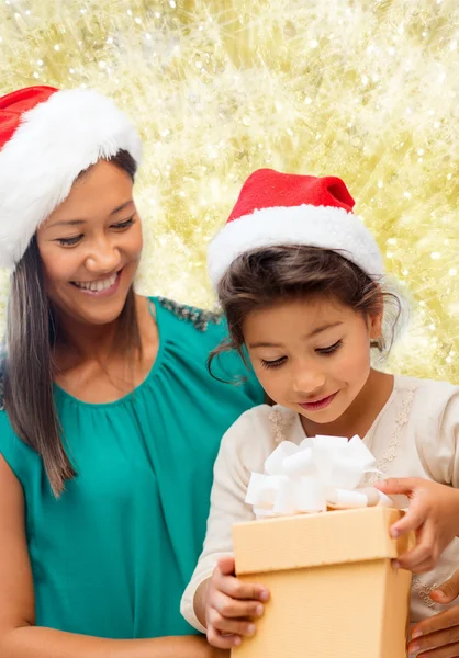 Glad mamma och flicka i santa hattar med presentask — Stockfoto