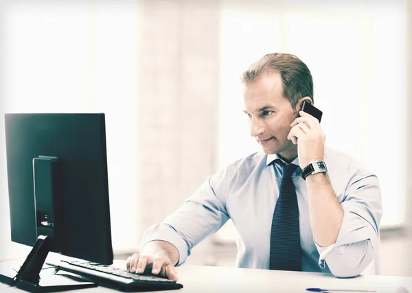 Hombre de negocios sonriente con teléfono inteligente en la oficina — Foto de Stock