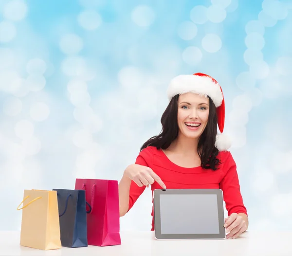 Lachende vrouw in Kerstman hoed met tassen en tablet pc — Stockfoto