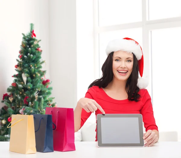 Leende kvinna i santa mössa med väskor och TabletPC — Stockfoto