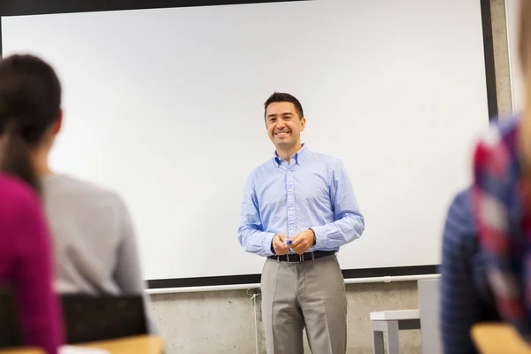 Group of students and smiling teacher in classroom — Stock Photo, Image