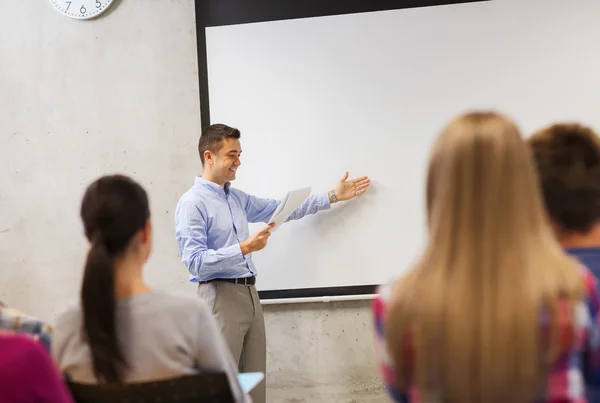 Schülergruppe und lächelnder Lehrer mit Notizblock — Stockfoto