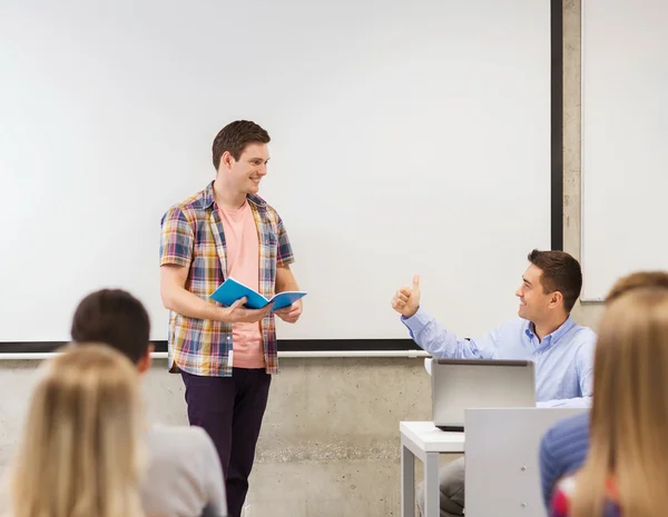 Group of smiling students and teacher in classroom — Stock Photo, Image
